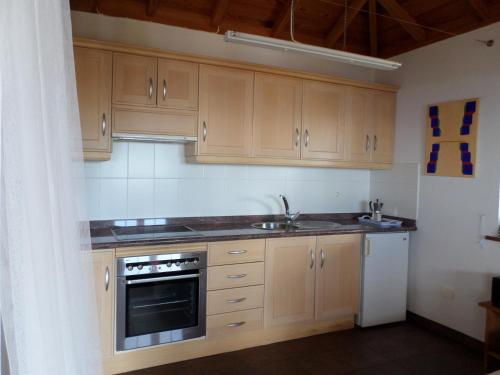 蓬塔戈尔达Casa Bellavista的厨房配有木制橱柜、水槽和烤箱。