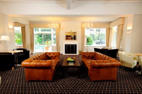 伯恩茅斯伯利府酒店的客厅配有2张真皮沙发和壁炉