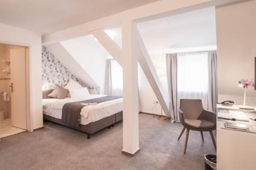 达姆施塔特霍夫古特迪普斯霍夫酒店及KG餐厅的一间卧室配有一张床、一张桌子和一把椅子