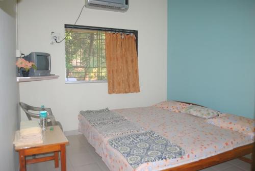 马尔万Hotel Anjali Lodge Malvan的一间卧室配有一张床、一台电视和一张桌子