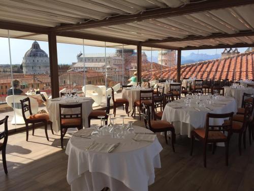 比萨杜尔墨大酒店的一间设有白色桌椅的餐厅,享有美景