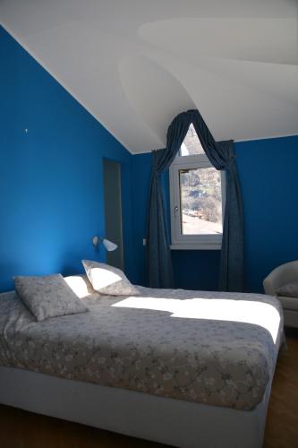 贝林佐拉德尔古斯托民宿的一间卧室设有蓝色的墙壁和一张带窗户的床