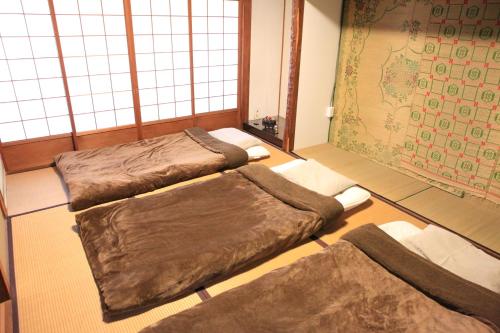 早岛町冈山蔺草旅舍的带窗户的客房内设有三张床。