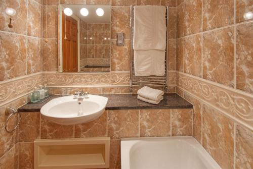 恩布尔顿The Dunstanburgh Castle Hotel的浴室配有盥洗盆和浴缸。