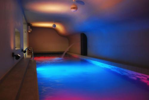 西维德尼察Hotel Fado Spa & Restaurant的室内的游泳池,有蓝色和红色的灯光