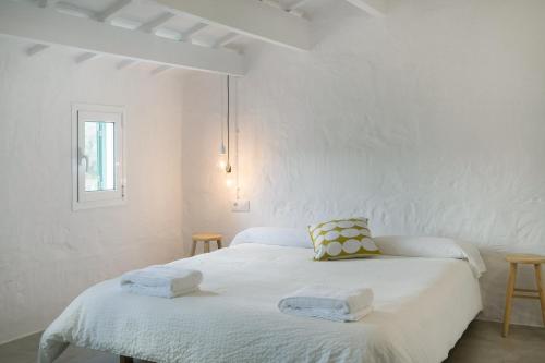 埃斯·梅卡达尔Cas Conco的白色卧室,配有带毛巾的床