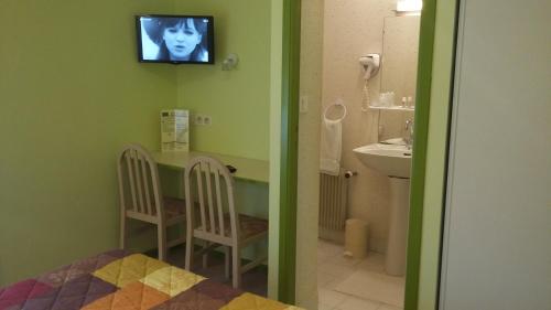 拉福雷富埃南Maison Hôtel Aux Cerisiers的一间带水槽的浴室和墙上的电视