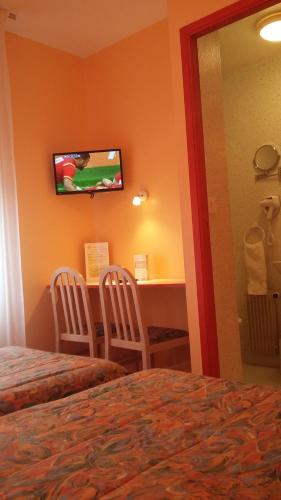 拉福雷富埃南Maison Hôtel Aux Cerisiers的酒店客房配有一张床、一张书桌和一台电视。