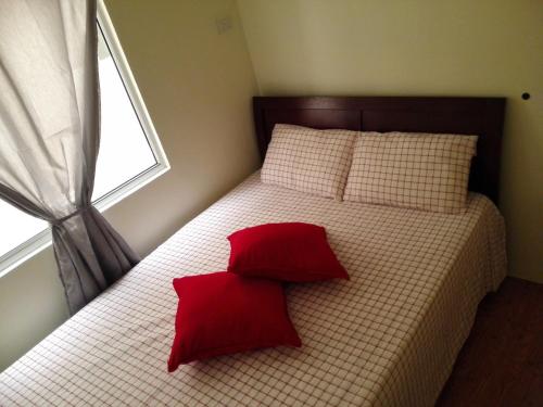 宿务圣雷莫绿洲公寓的一间卧室配有一张带红色枕头的床和一扇窗户
