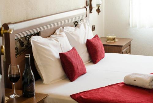 Rozhen丁科瓦库什塔家庭酒店的一张带红白枕头的床和一杯葡萄酒