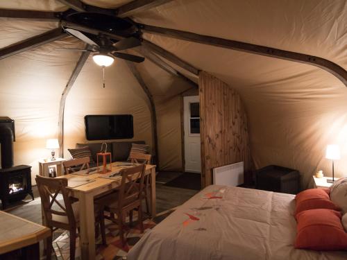 罗登Yourtes - Chalets Lanaudière的帐篷内带一张床和一张桌子的房间