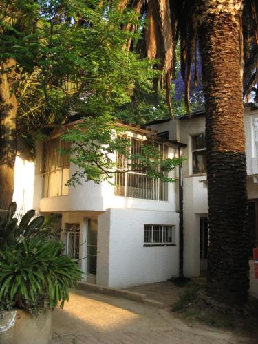 约翰内斯堡Rosebank Hostel的一座白色的建筑,前面有棕榈树
