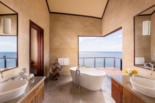 CulebraFour Seasons Resort Peninsula Papagayo, Costa Rica的一间设有两个盥洗盆和浴缸的浴室,享有美景。