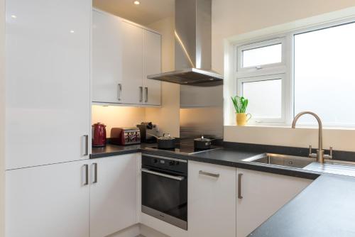 牛津North Parade Avenue的厨房配有白色橱柜、水槽和窗户。