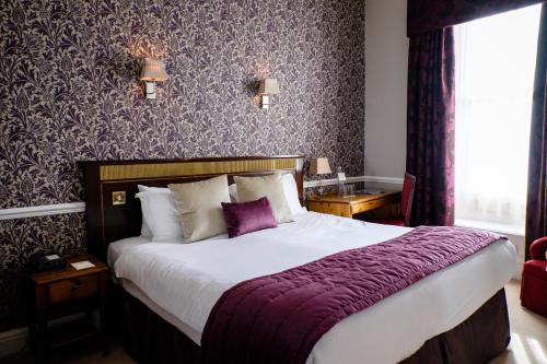 巴克斯顿老霍酒店的一间卧室配有一张大床和紫色毯子
