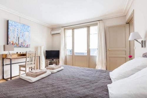 巴黎1 Square du Docteur Blanche - Paris 16的一间卧室配有一张大床、一张桌子和一台电视机。