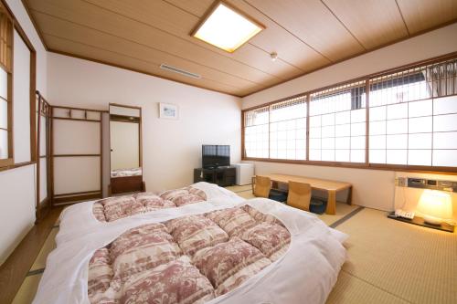 Yōkaichi八日市皇家酒店 的一间卧室设有一张大床和两个窗户。