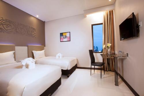 雅加达Verse Lite Hotel Gajah Mada的酒店客房设有两张床和电视。