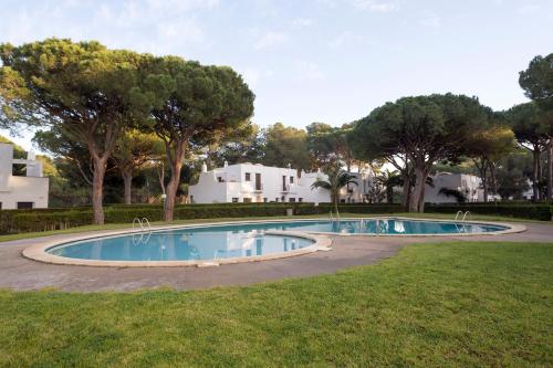 帕尔斯Casas en Piverd del Golf的一座带树木和房屋的庭院内的游泳池