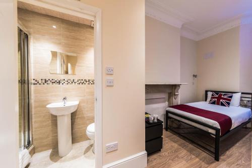 伦敦萨巴梅兰德酒店的一间卧室配有床、水槽和卫生间