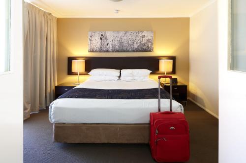 布里斯班威斯恩中央公寓酒店的酒店客房,配有一张带红色手提箱的床