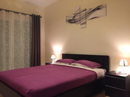 萨伊迪耶Appartement Saidia Méditerranée的一间卧室配有一张大床,提供紫色床单和枕头