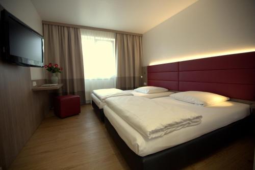 默费尔登-瓦尔多夫Airport Hotel Walldorf的酒店客房设有两张床和一台平面电视。