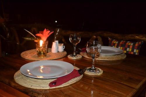 曼巴豪甘米银沙滩生态火山度假&潜水胜地的一张木桌,上面放有盘子和酒杯