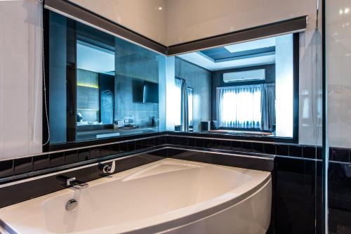 武里南Cresco Hotel Buriram的带窗户的浴室设有大浴缸