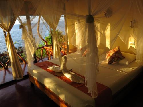 曼巴豪甘米银沙滩生态火山度假&潜水胜地的一间卧室设有一张床,享有海景