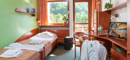 特伦钦温泉镇Hotel Flóra的客房设有两张床、一张桌子和一个窗户。