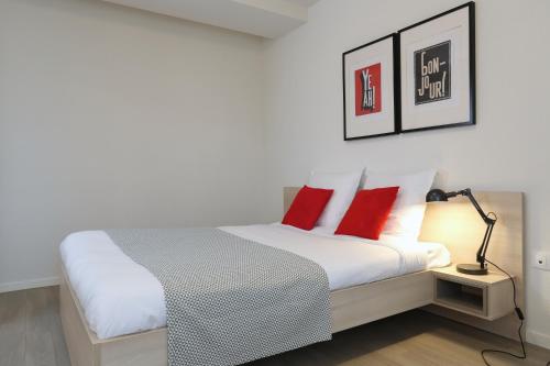 南希南锡公寓式酒店的一间卧室配有一张带红色枕头和一盏灯的床