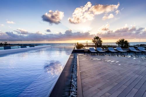 科斯塔特吉塞巴塞罗特吉塞海滩酒店 - 仅限成人的一个带椅子的游泳池,背景是大海