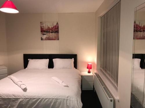 赫尔Victoria Parade Apartment的一间卧室配有一张带白色床单和红灯的床。