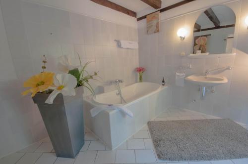 埃尔克拉特佳斯特豪斯瓦恩穆勒酒店的带浴缸、水槽和花瓶的浴室