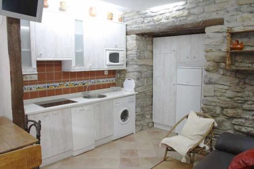 Menagaray鲁拉尔林孔艾亚拉公寓的一间厨房,配有白色家电和石墙