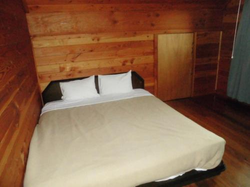 白马村哈普木屋别墅 的卧室配有白色的木墙床