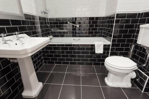AshfordChester Beatty Inn的黑色瓷砖浴室设有卫生间和水槽
