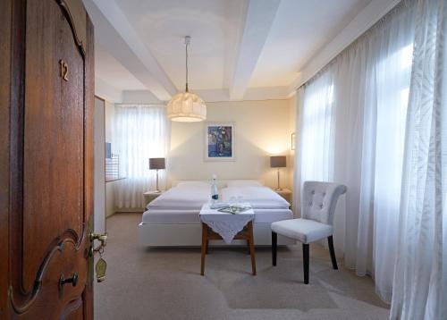 OberhundemHotel Gasthof Zu den Linden的卧室配有1张床、1张桌子和1把椅子