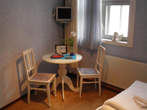 吕贝克菲林豪斯维图切特旅馆的配有桌子和两把椅子及一张床的房间