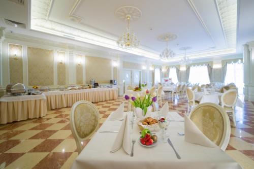 雅罗斯瓦夫雅罗斯瓦夫酒店的一个带白色桌椅的大型宴会厅