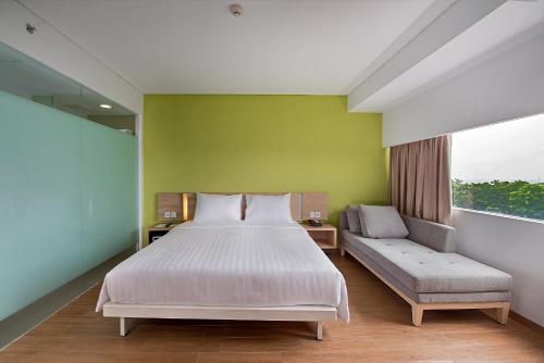 茂物微姿普莱姆帕加加阳博格尔酒店的一间卧室配有一张床、一张沙发和一个窗口