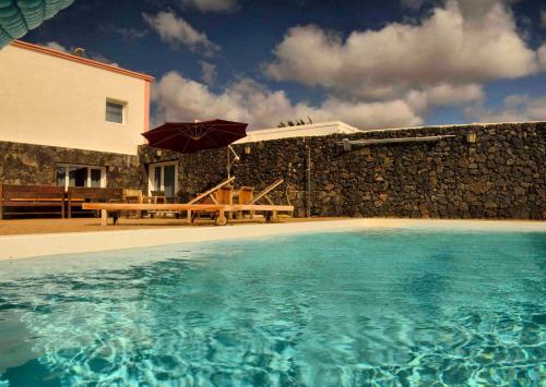 卡列罗港Casa Juanita的一座带游泳池、桌子和遮阳伞的房子
