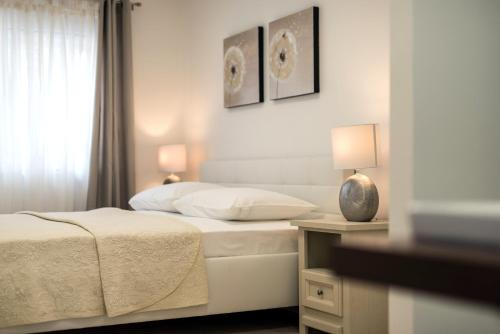 扎达尔Eden Apartments的一间白色卧室,配有两张床和窗户
