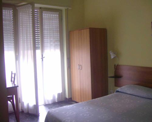 因佩里亚Pensione Aurora的一间卧室配有一张床和一个木制橱柜