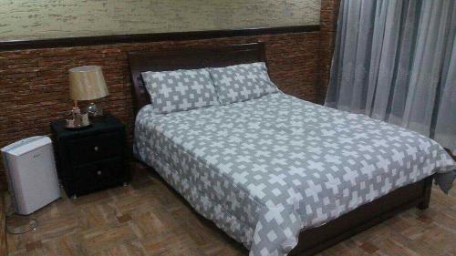 碧瑶Affordable Baguio APT的一间卧室配有一张床和一个带灯的床头柜