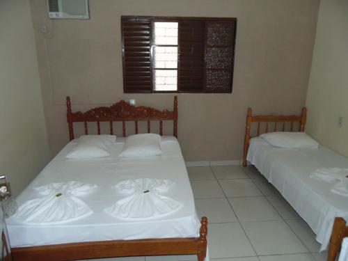 普鲁登特总统城Avenida Hotel的一间卧室设有两张带白色床单的床和窗户。
