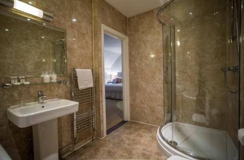 亚特利The Casa Hotel-Yateley, Farnborough的浴室配有水槽、淋浴和浴缸。