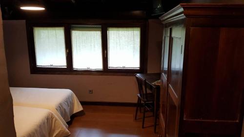 埃利松多Hostal Itzalargikoborda的一间卧室设有2个窗户、一张床和一张书桌