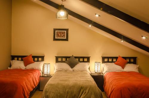 库斯科库斯科住宿加早餐旅馆的一间卧室配有两张带橙色和白色枕头的床